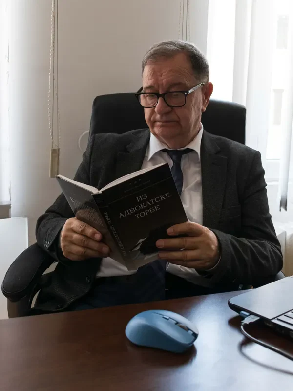 Advokat Mileta B. Radojević pruža pravne usluge u Beogradu, prikazan dok čita advokatsku knjigu